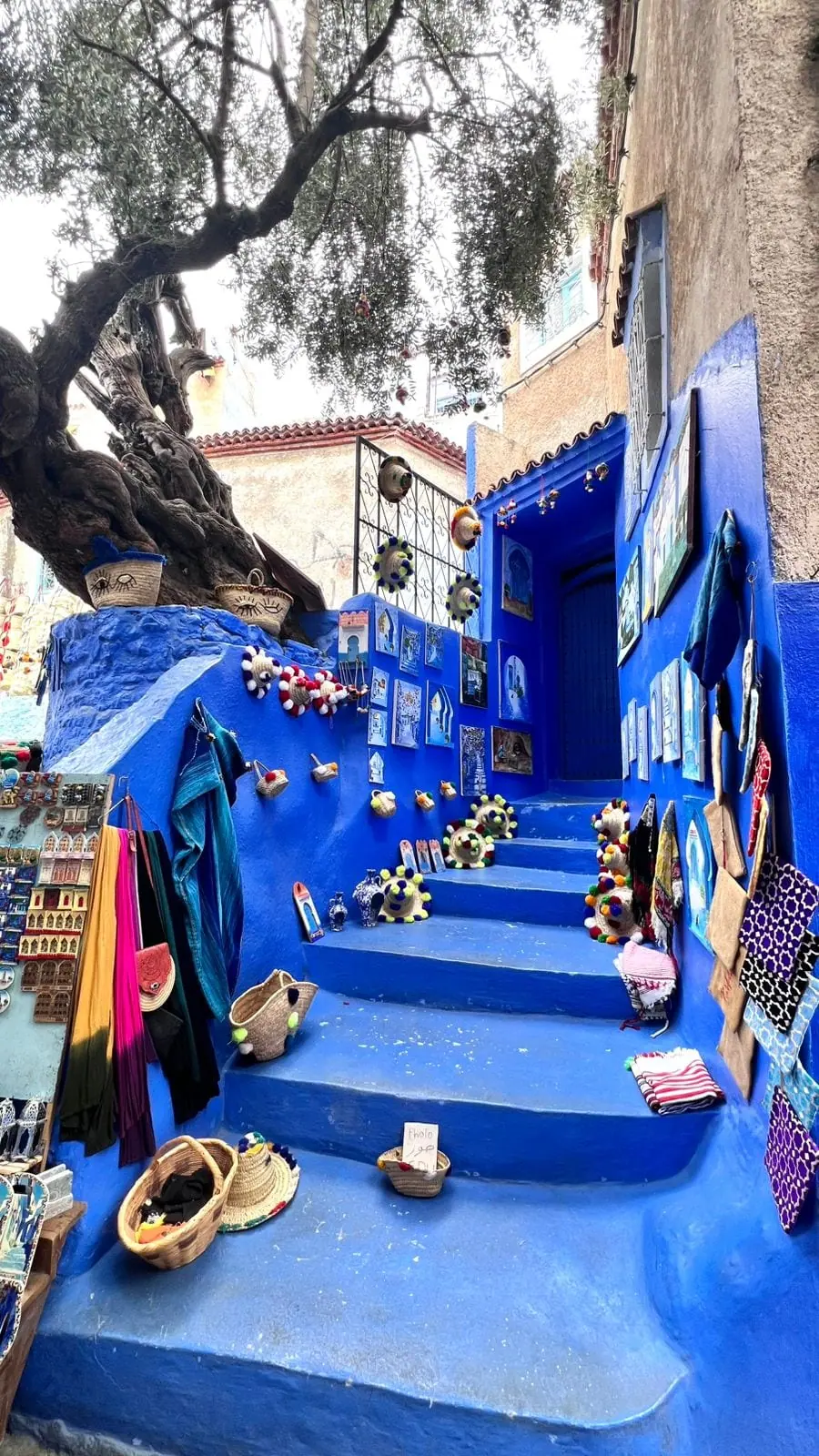 Escadas azuis com artesanato numa ruela de Chefchaouen, a cidade azul do Marrocos
